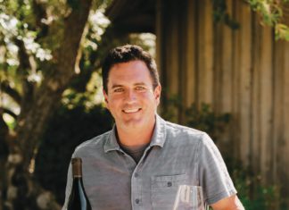 Winemaker Joe Nielsen holding a bottle and glass of Ram's Gate red wine.